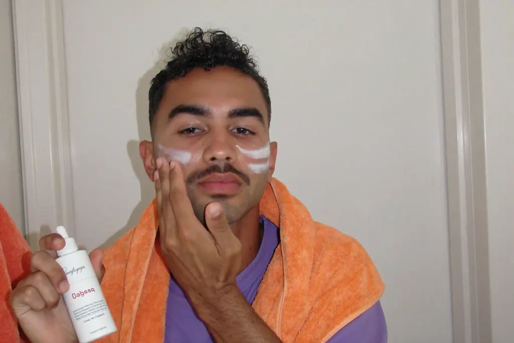 Hombre aplicándose sérum con las yemas de los dedos